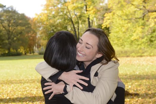  happy girlfriends hugging in autumn park