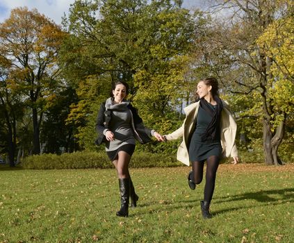  happy sisters running in autumn park