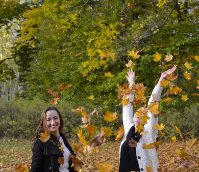 laughing sisters throwing autumn leaves