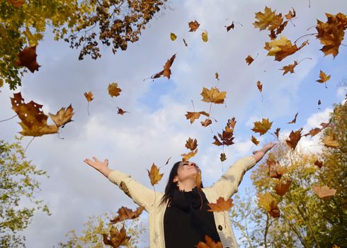  beautiful young woman throwing autumn leaves