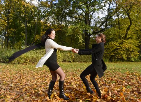 happy young women dancing in autumn park
