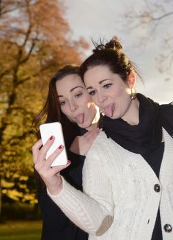 cheeky girlfriends with smartphone in autumn park