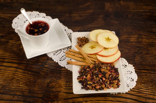 Cup of fruity tea with its  main ingredients