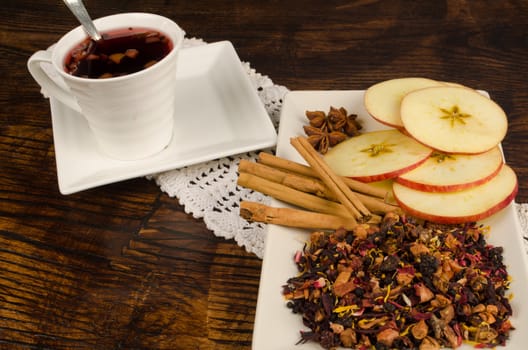 Cup of fruity tea with its  main ingredients