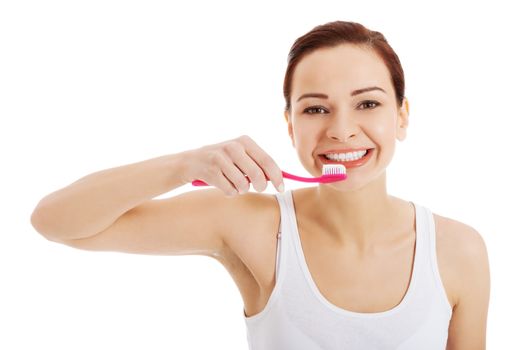 Beautiful woman in white top is brushing her teeth. Isolated on white.