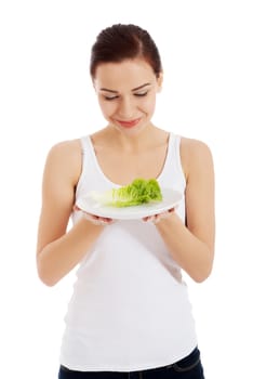 Young beautiful woman holding leaf of lettuce on table. Isolated on white.