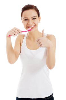 Beautiful woman in white top is brushing her teeth and showing OK. Isolated on white.