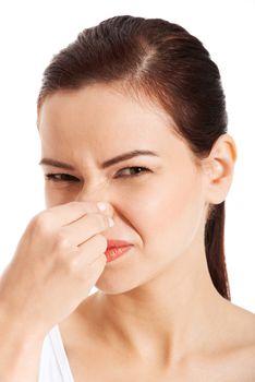 Portrait of a young woman holding her nose because of a bad smell. Isolated on white.