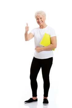 An old woman holding workbook and showing OK. Isolated on white.