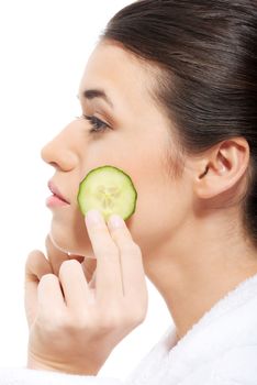 Beautiful woman in bathrobe holding slices of cucumber on her face. Isolated on white.