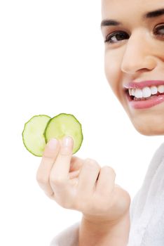 Beautiful woman in bathrobe holding slices of cucumber. Isolated on white.