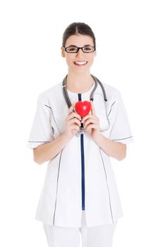 Beautiful young female doctor holding a heart. Isolated on white.