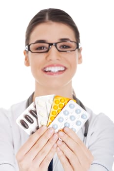 Young female doctor holding pills. Isolated on white.