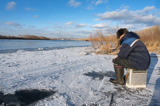 The fisherman on winter fishing in frosty day