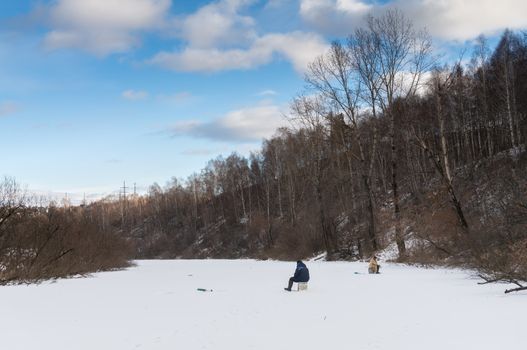 The fisherman on winter fishing in frosty day