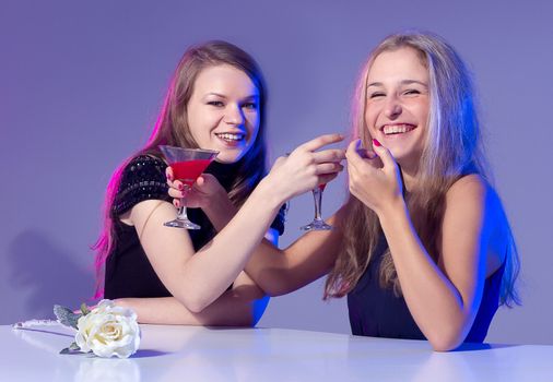 Female friends enjoying a night out sitting having cocktails at a table in a nightclub