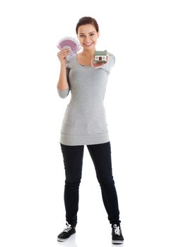 Beautiful young, casual woman holding money and house. Isolated on white.