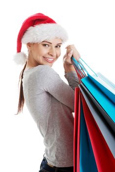 Beautiful woman in santa hat carrying shopping bags. Isolated on white.