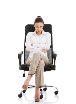 Young sad business woman sitting on a chair. Isolated on white.