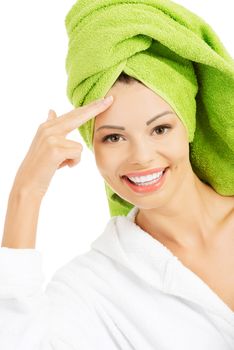 Beautiful woman in bathrobe and turban is touching her forehead. Isolated on white.