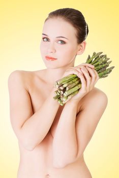 Beautiful fit woman with asparagus, over yellow