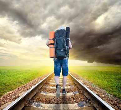 Tourist on the railroad under cloudy sky