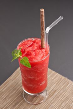 Red fruit flavored frozen cocktail or smoothie beverage with straw and stirring stick.