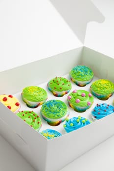 Colorful decorated cupcakes in a white box