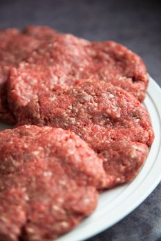 Raw fresh hamburgers on a white platter