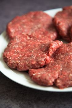 Raw fresh hamburgers on a white platter