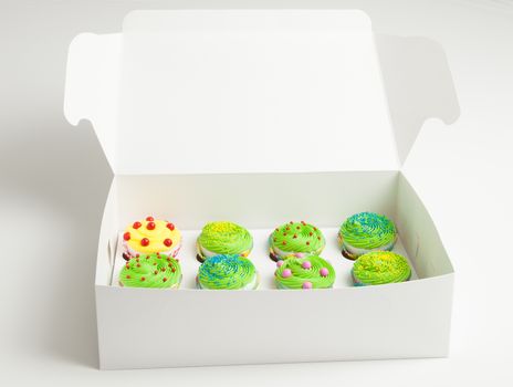 Colorful decorated cupcakes in a white box