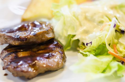 food steak on white dish with salad and bread