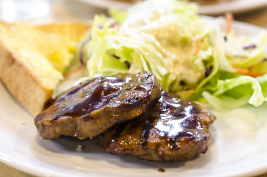 food steak on white dish with salad and bread