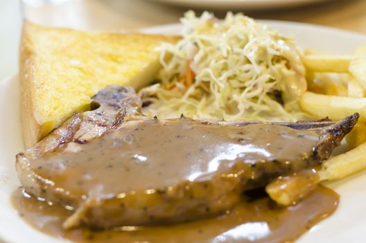 food steak on white dish with salad and bread