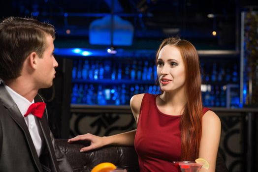 portrait of a woman in a nightclub, sitting on the couch and talking with man