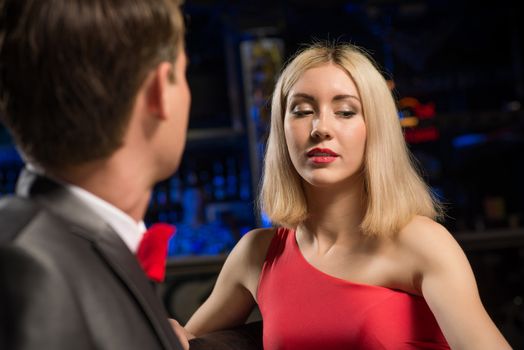 portrait of a woman in a nightclub, sitting on the couch and talking with man