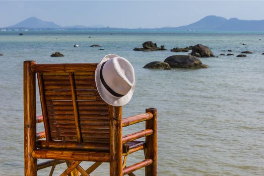 Hat hangs on a wicker chair on the background of the sea