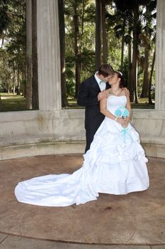 A handsome groom kisses his beautiful bride outdoors.