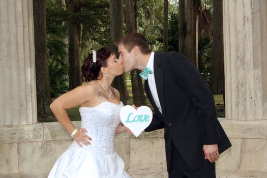 A handsome groom kisses his beautiful bride outdoors.