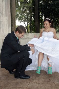 A handsome groom prepares to remove the garter from his bride's leg.