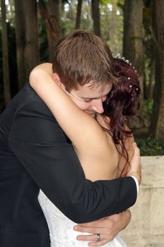 A handsome groom embraces his bride outdoors.