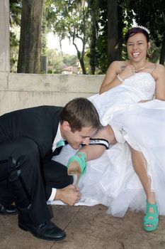 A handsome groom removes the garter from his bride's leg with his teeth.