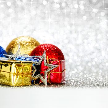 Christmas decorative balls and gifts over shiny stars background