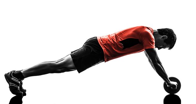 one man exercising fitness workout abdominal toning wheel in silhouette on white background