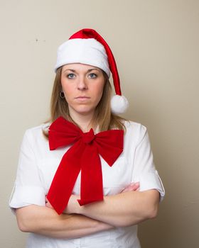 During christmas time a woman in a santa hat and a bow doesn't look happy