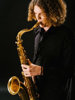 Photo of a teenager playing the saxophone over dark background.
