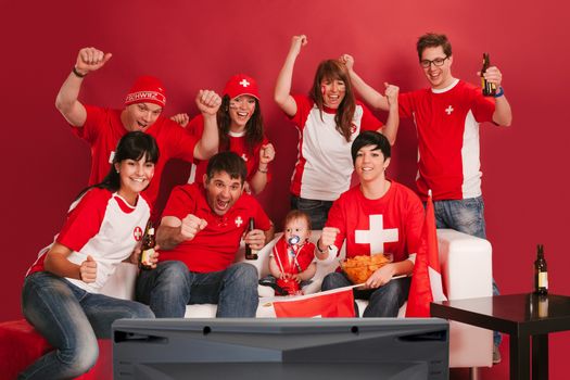 Photo of Swiss sports fans watching television and cheering for their team.