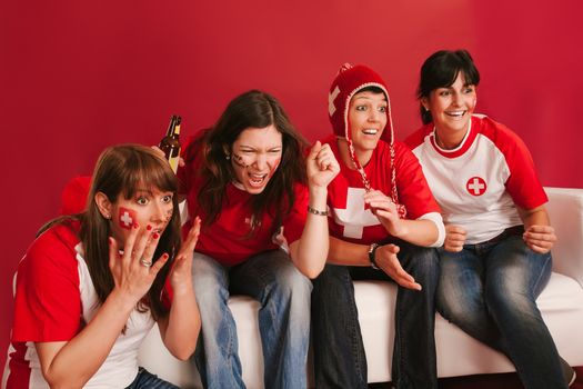 Photo of female Swiss sports fans watching television and cheering for their team.
