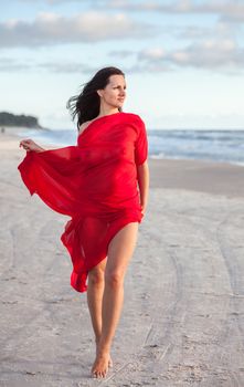 Young naked woman on a beach with red fabric
