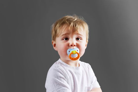Cute little blond baby boy or toddler with pacifier